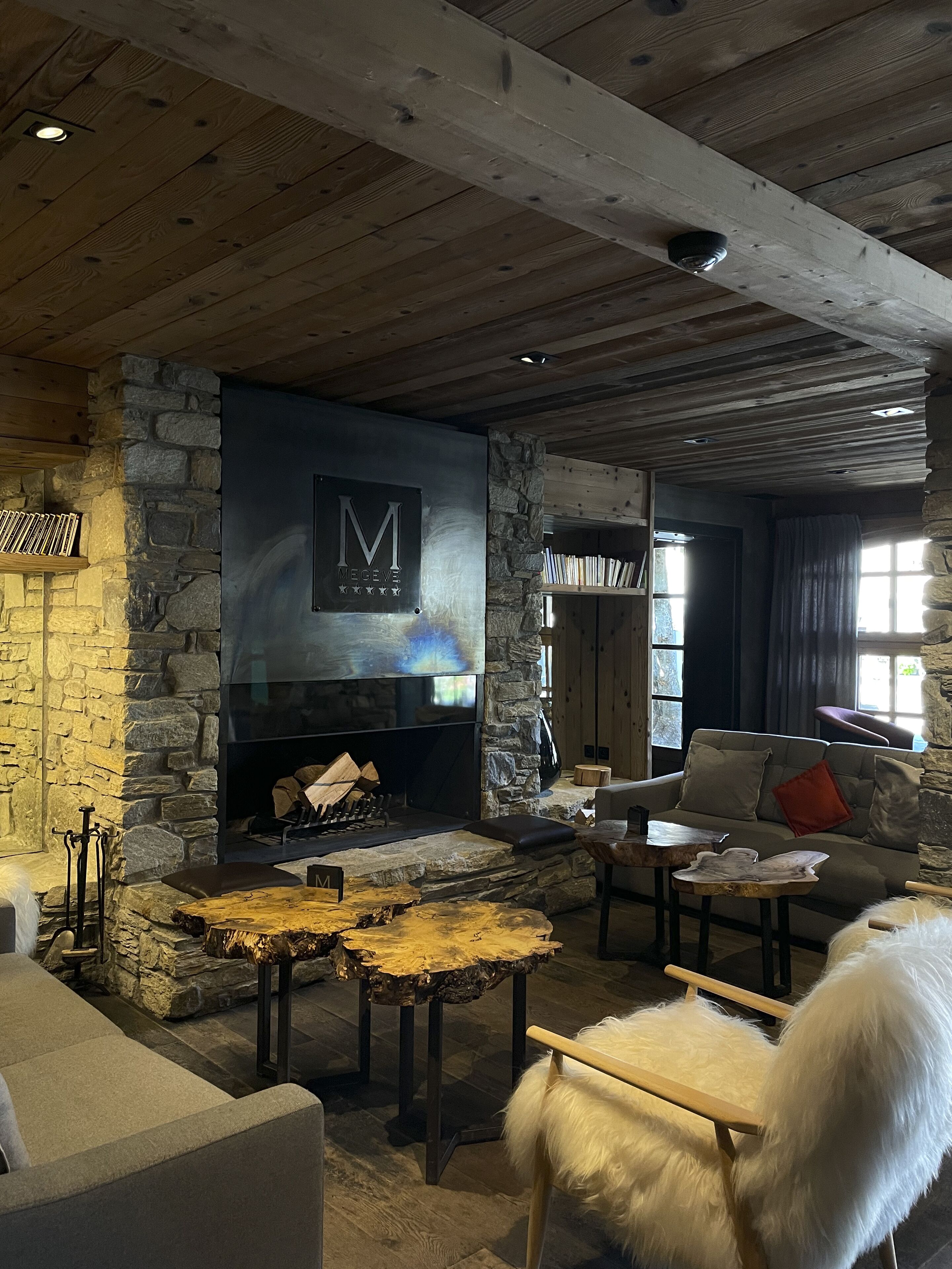 Un salon chaleureux avec une cheminée en pierre, un mur en pierre et un plafond en bois.