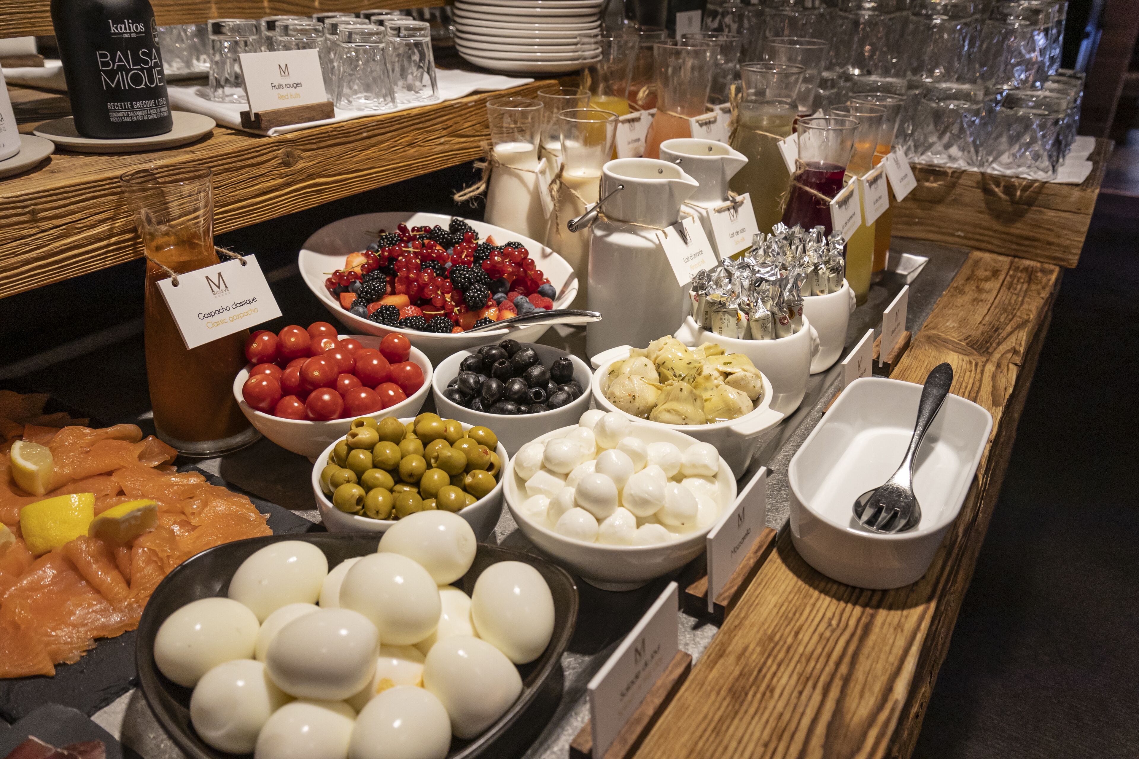 Buffet com diversos alimentos, incluindo ovos, azeitonas, tomates e queijo.