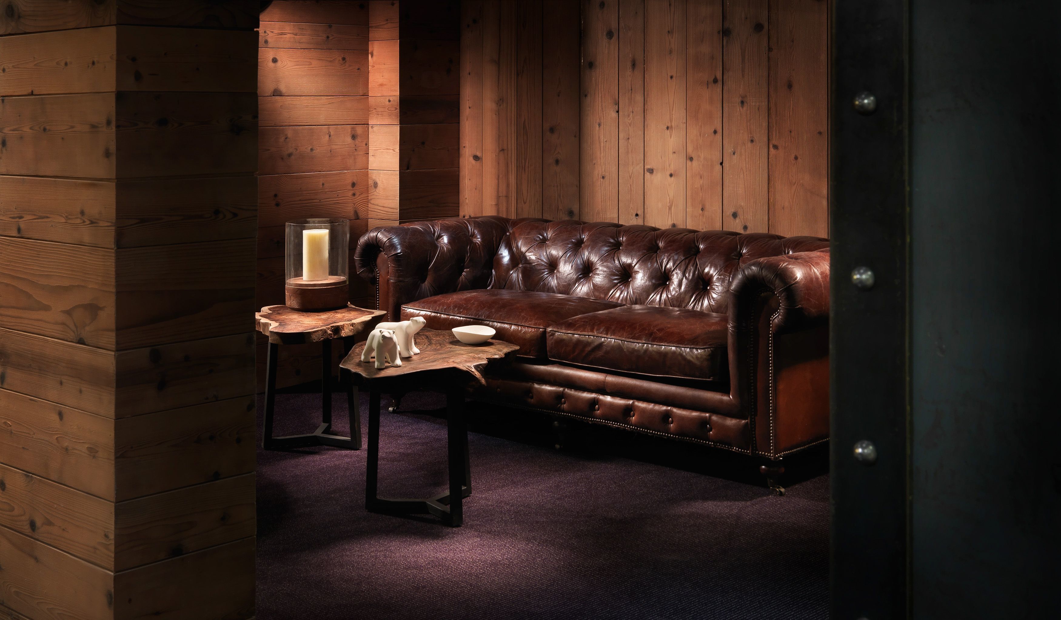A cozy room with a leather sofa, a small wooden side table with a candle, and a polar bear figurine.