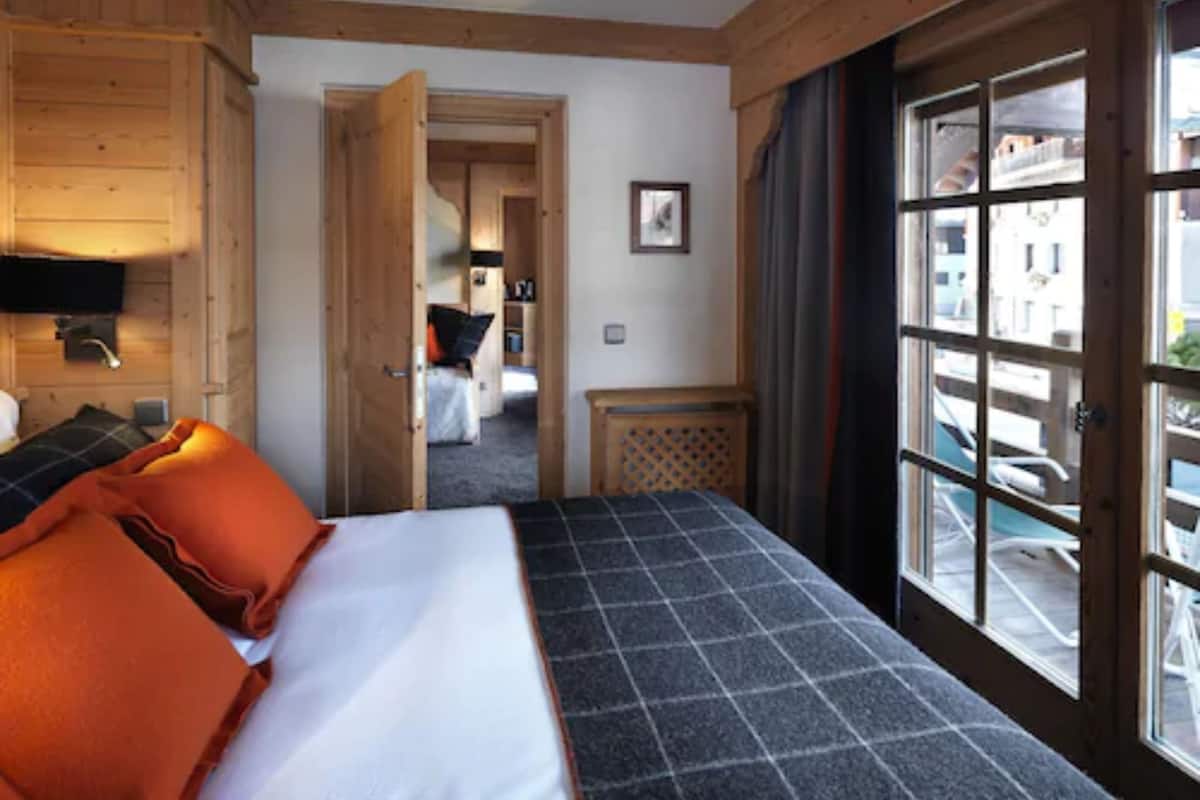 A hotel room with a bed, a television, and a view of the outside.