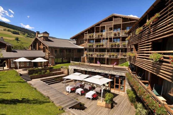 A wooden lodge with outdoor seating and a deck. - Le M de Megève (Megeve)