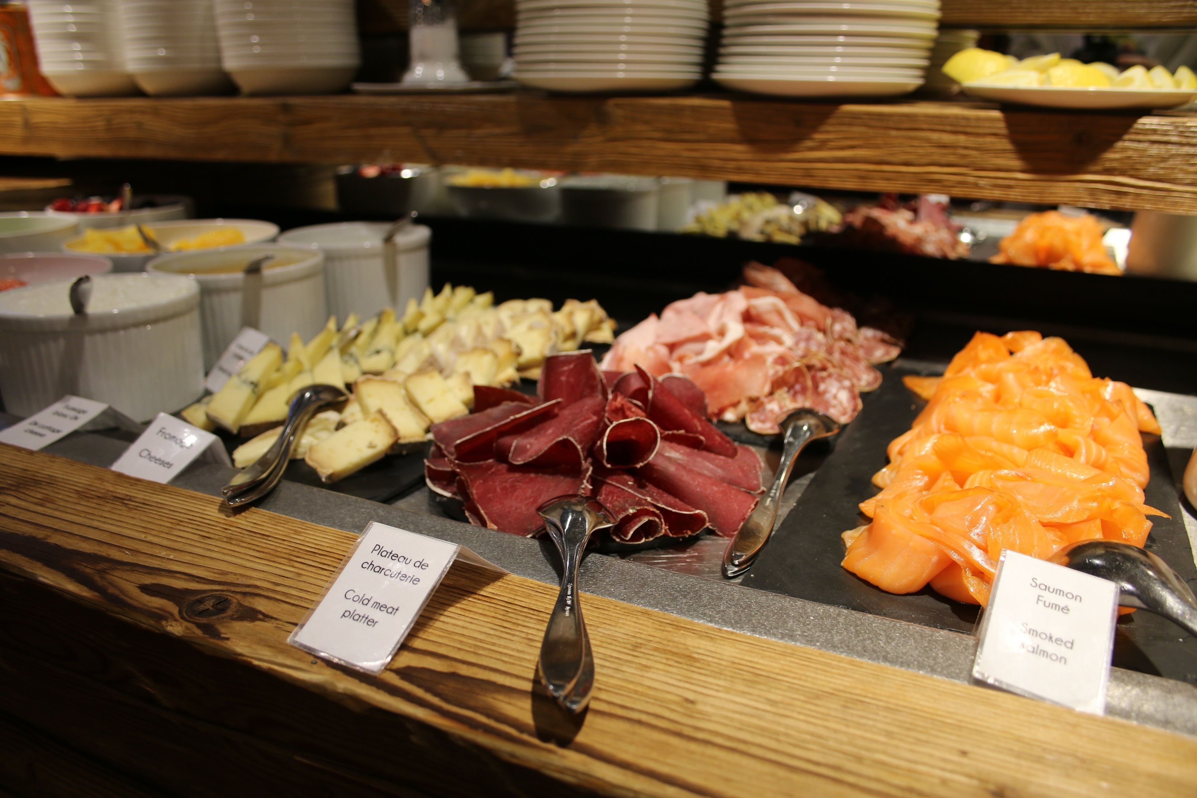 A buffet with various cold cuts and cheeses, including prosciutto, salami, and smoked salmon.