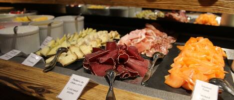 A buffet with various cold cuts and cheeses, including prosciutto, salami, and smoked salmon.