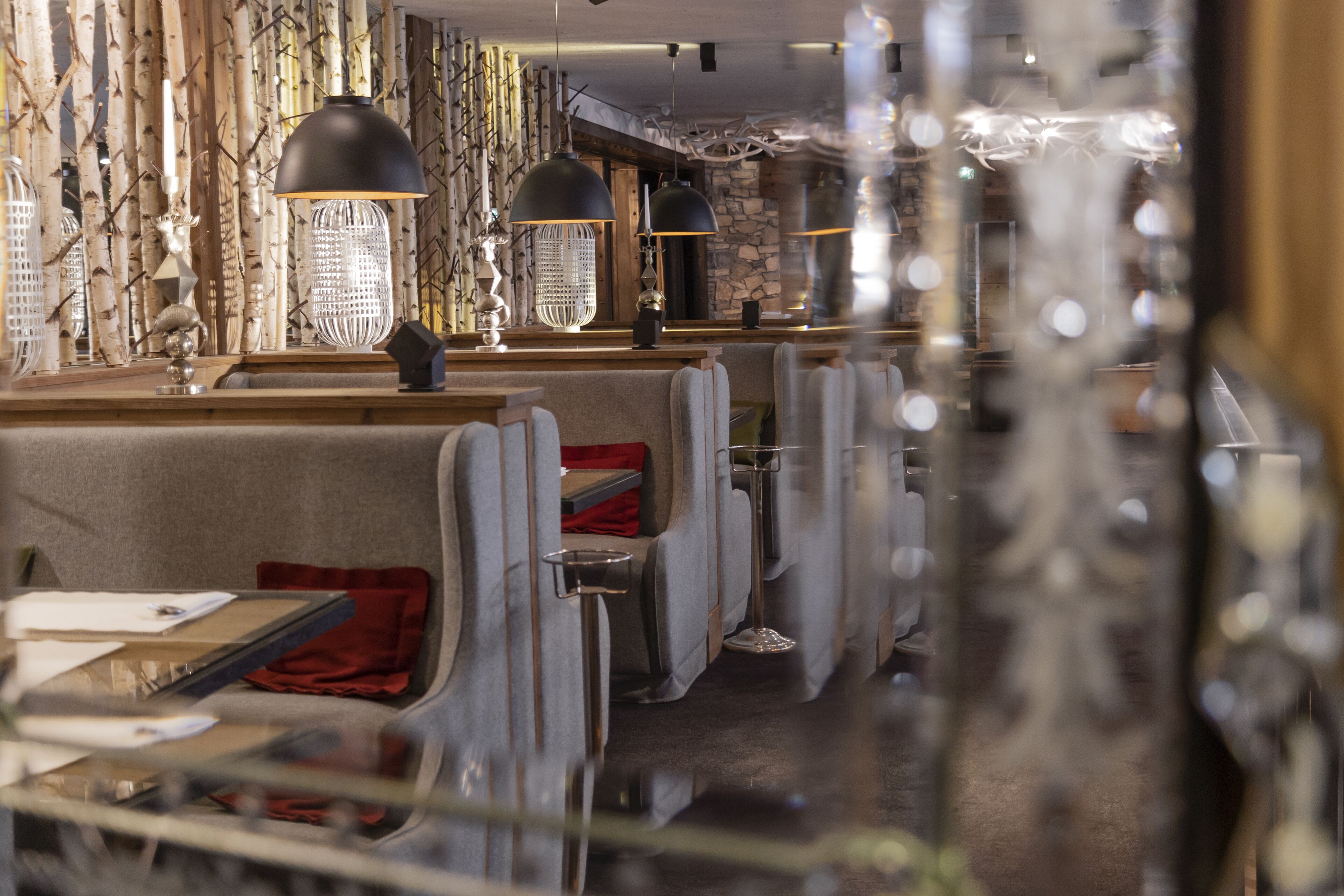 Un restaurant avec des banquettes, des tables et des lampes suspendues.
