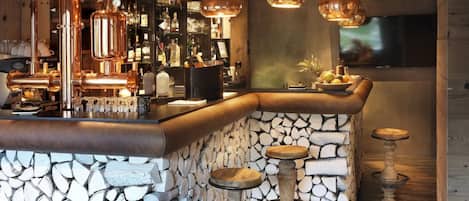 A bar area with a stone wall, wooden logs, and metal stools.