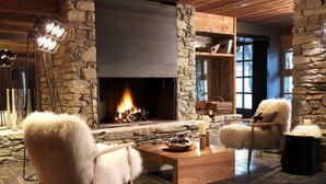 Une pièce chaleureuse avec une cheminée en pierre, des meubles en bois et une grande fenêtre.