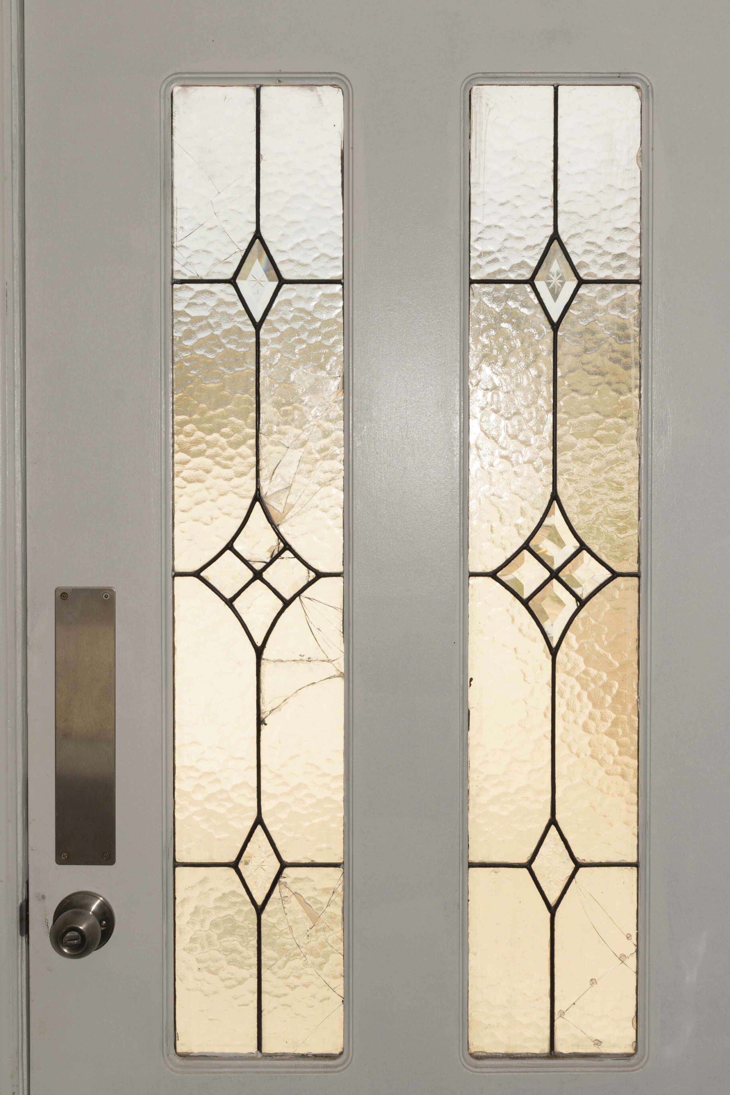 A door with two vertical glass panels featuring diamond-shaped patterns and a metal handle.