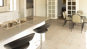 Una cocina moderna con una isla grande, taburetes de bar y un área de comedor con sillas y una mesa.