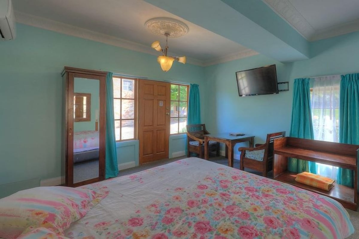 Un dormitorio con cama, escritorio, silla, televisor y armario.
