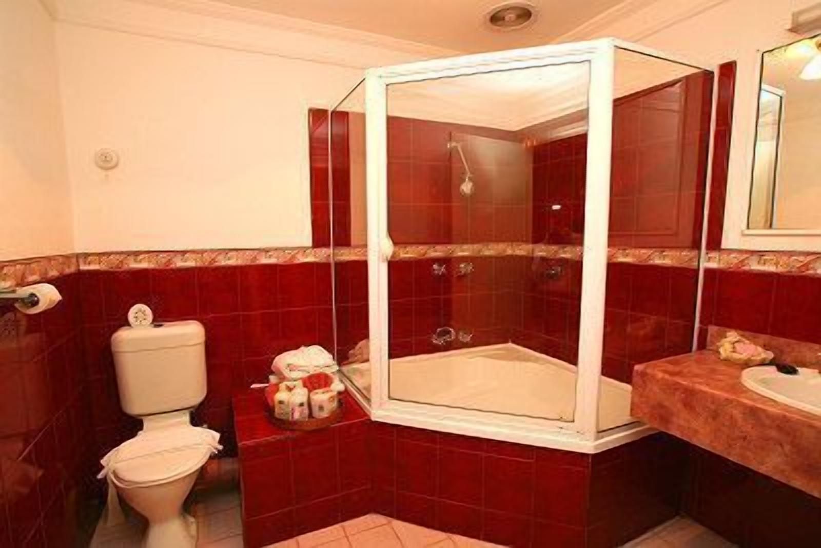 A bathroom with a glass-enclosed shower, a toilet, and a sink.