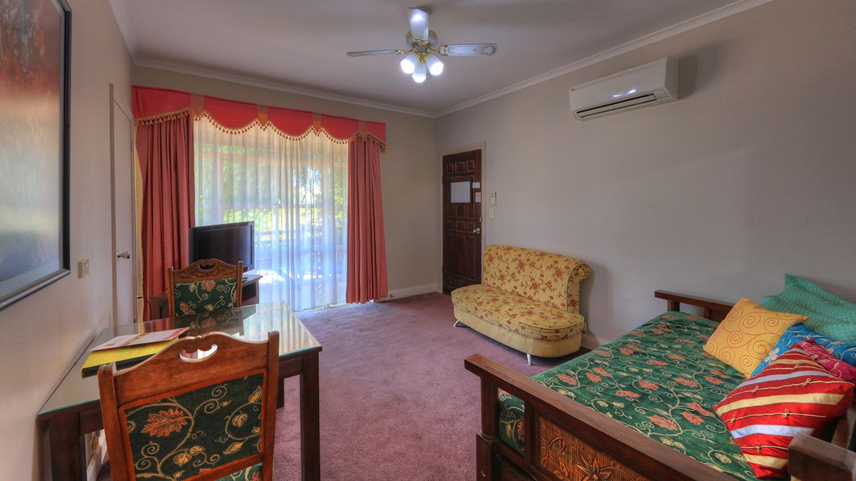 A room with a bed, a chair, a table, and a television.