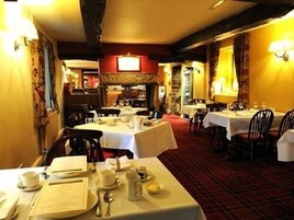 Un restaurante con mesas dispuestas para comer, que presenta una alfombra roja y manteles blancos.