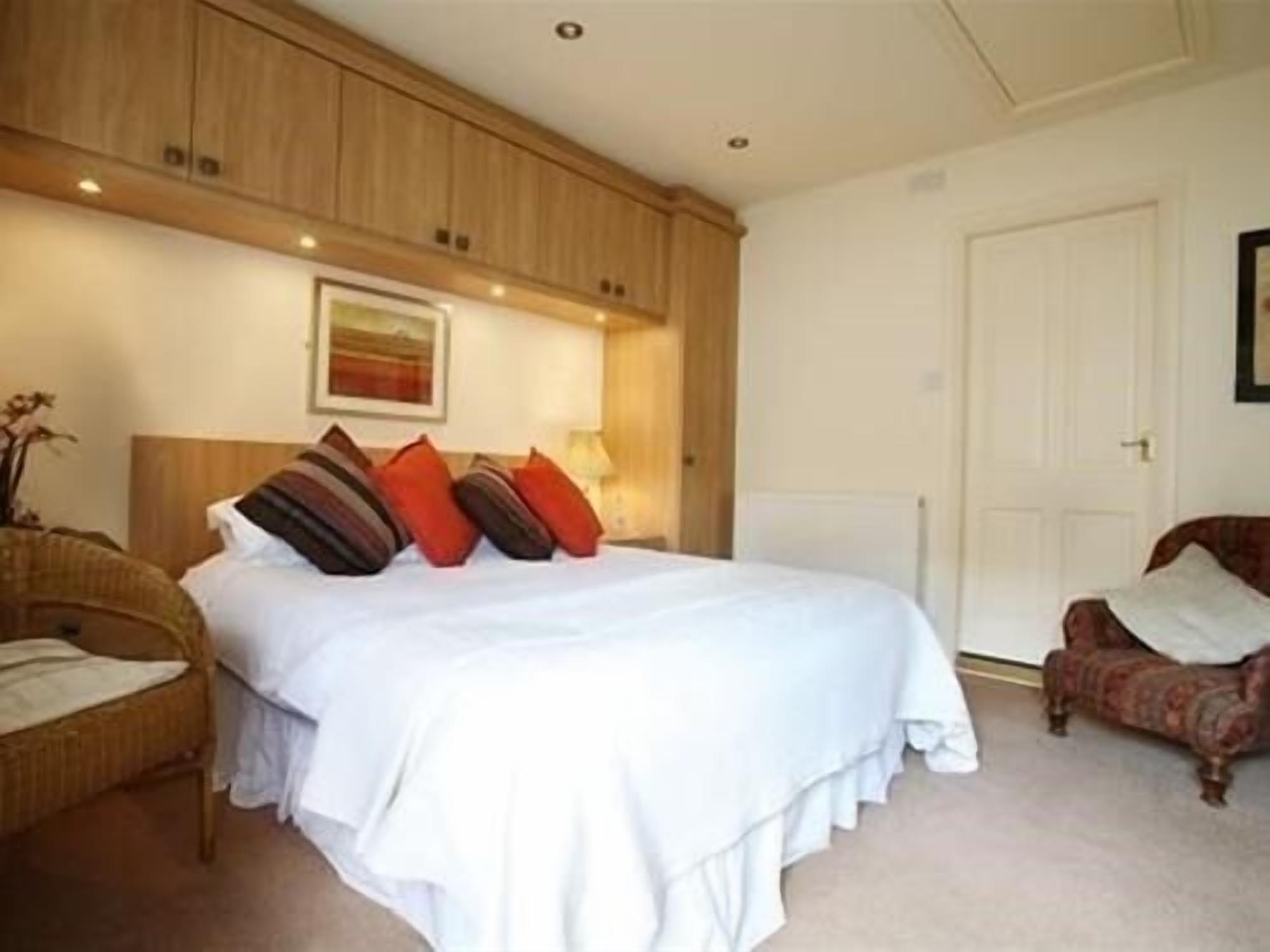 Une chambre à coucher avec un grand lit, une tête de lit en bois, une chaise et une porte.