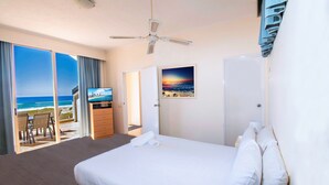 A hotel room with a large bed, a ceiling fan, a TV, and a view of the beach. - Sand Castles on Currumbin Beach (Currumbin)