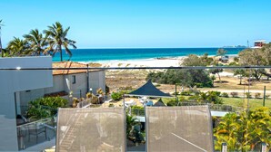 A balcony with a view of the beach, palm trees, and a clear blue sky. - Sand Castles on Currumbin Beach (Currumbin)