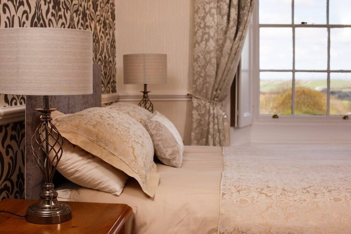 A bedroom with a bed, two bedside lamps, and a window with curtains.