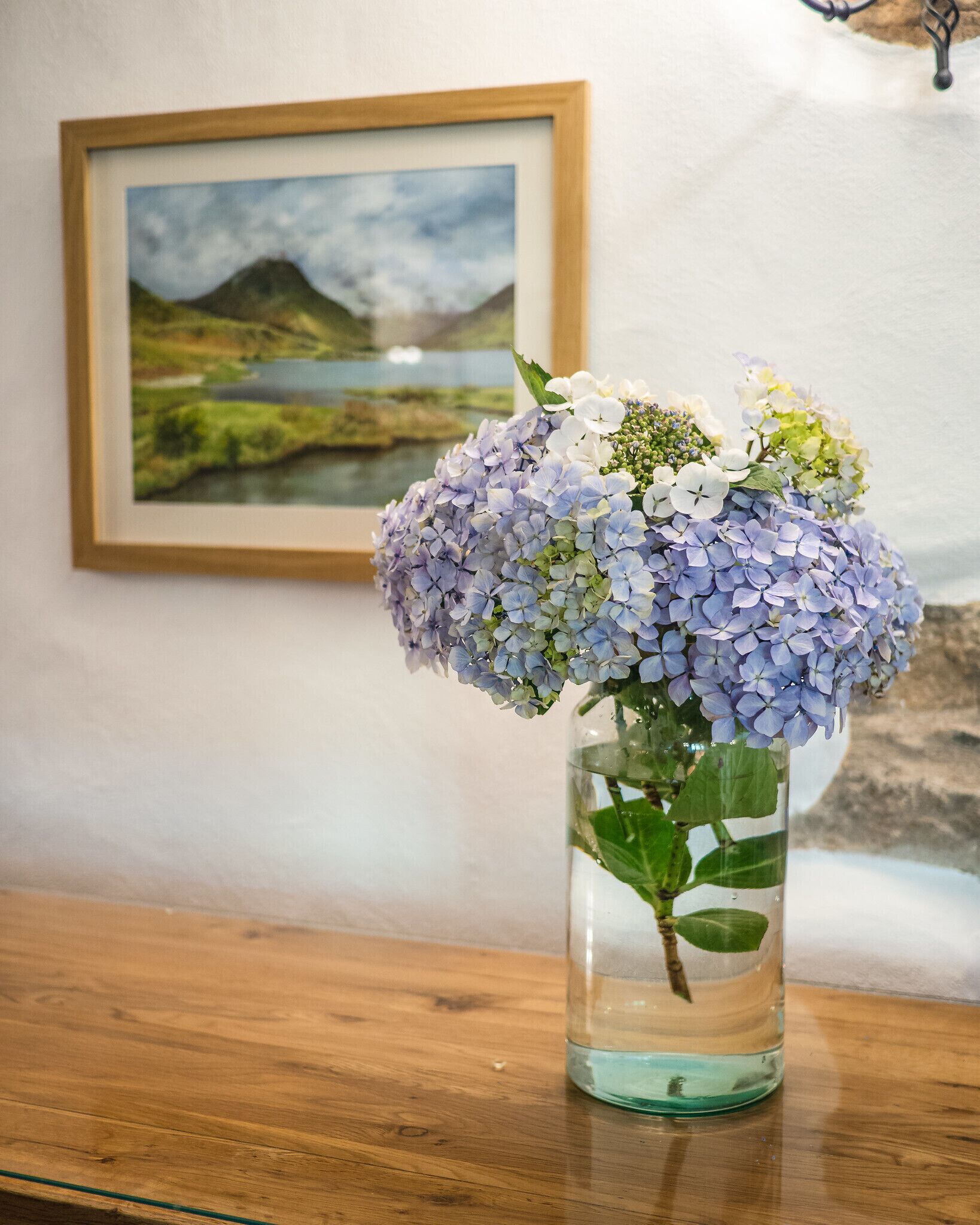 A vase with hydrangea flowers on a wooden table.