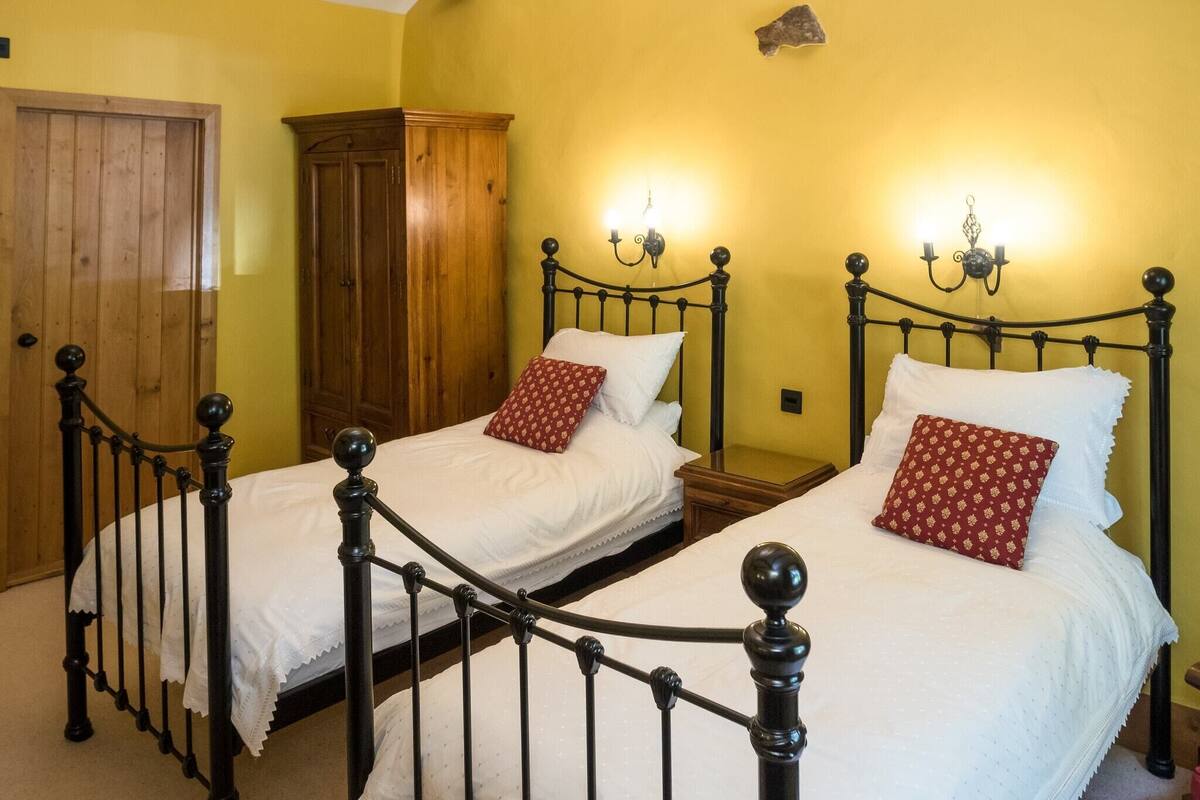 A room with two single beds, wooden wardrobe, and a door.