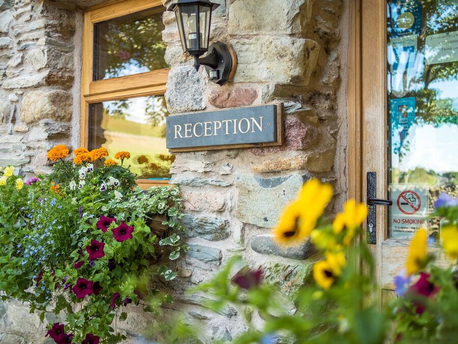 A stone building with a reception sign, a window, and a no-smoking sign.