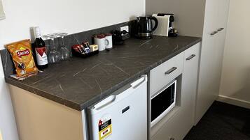 A compact kitchenette with a refrigerator, a coffee maker, and a toaster.