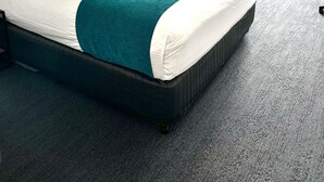 A hotel room with a large bed, a desk, and a chair.
