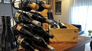 A wine rack with multiple bottles on a wooden counter in a room with a modern design.