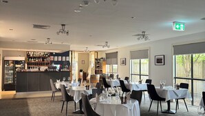 A restaurant with multiple tables, chairs, and a bar area.