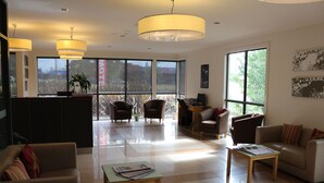 A spacious lobby with a reception desk, seating area, and large windows.