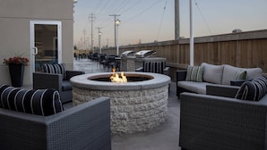 Un patio al aire libre con mobiliario de mimbre, un hogar de piedra y una valla de madera.