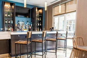 Un'area bar con diversi sgabelli e scaffali pieni di bottiglie.