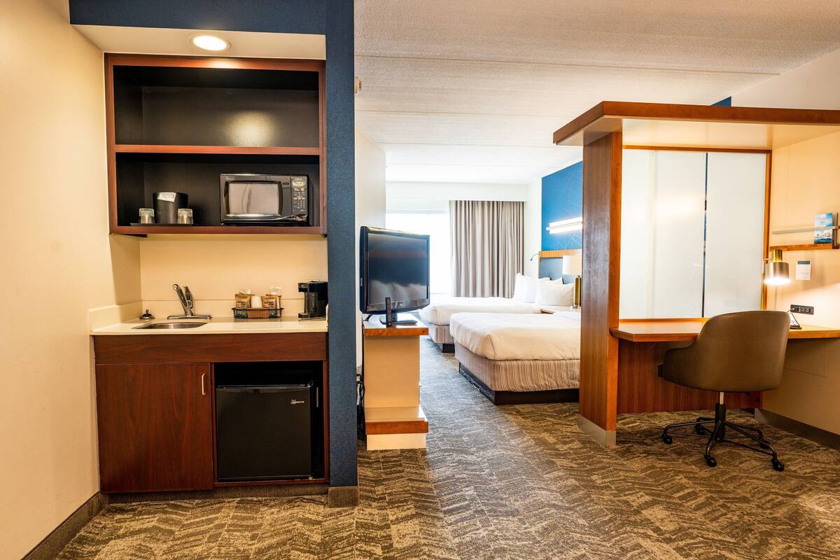 Une chambre d’hôtel équipée d’une kitchenette, d’un lit, d’un bureau et d’une chaise.