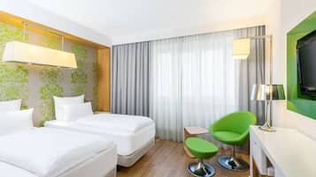 Une chambre d’hôtel avec deux lits, un bureau, une chaise, une télévision et une fenêtre avec des rideaux.