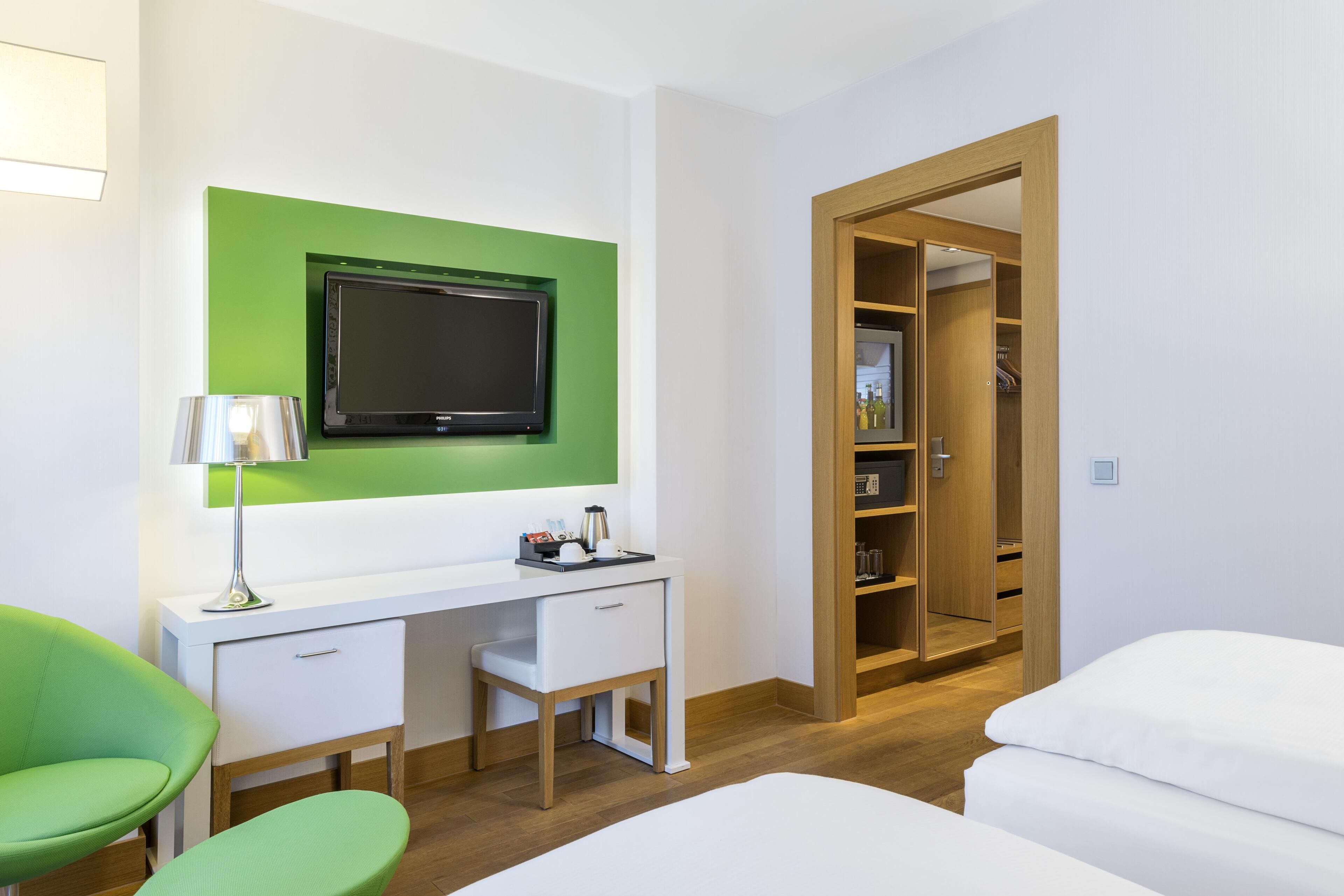 Une chambre d’hôtel équipée d’un bureau, d’une chaise, d’un lit et d’une armoire.