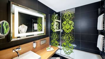 Un baño moderno con un espejo grande, un lavabo, ducha con puertas de vidrio decorativas y un perchero para toallas.