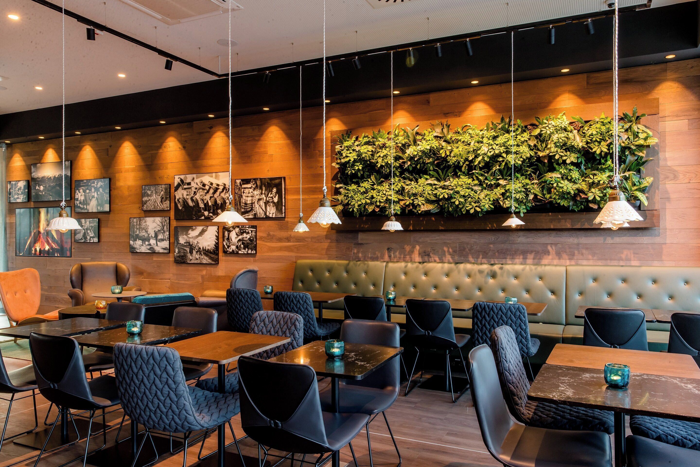 Un restaurante moderno con paredes de madera, asientos tapizados en negro y gris, y lámparas colgantes.
