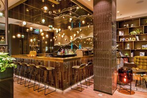 A bar area with multiple stools, a bar counter, and hanging spherical light fixtures. - Motel One Salzburg-Süd (Salzburg)