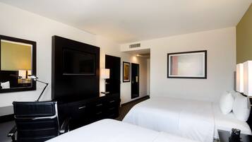 A hotel room with two beds, a desk with a chair, a TV, and a mirror.