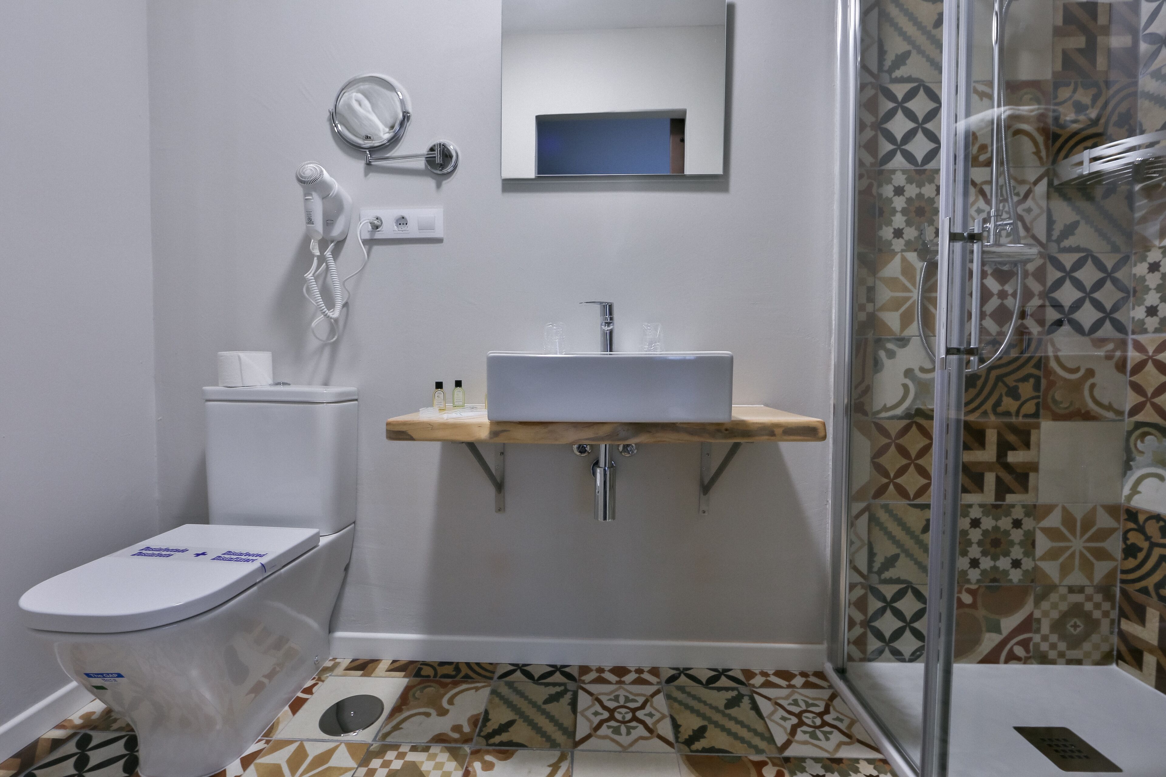 A bathroom with a toilet, a sink with a mirror above it, and a shower area.