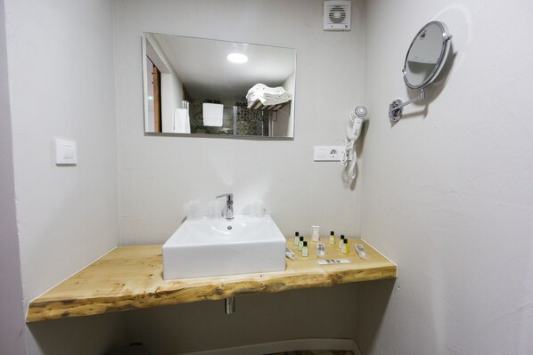A bathroom with a wooden vanity, a white sink, a mirror, and a hairdryer. - Hotel Playa de Camariñas (Camarinas)
