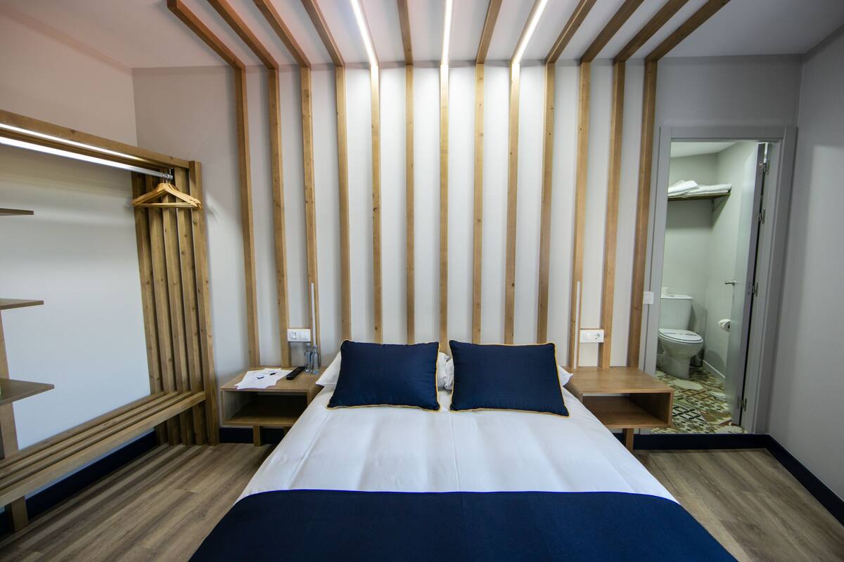 Ein Hotelzimmer mit einem Bett, einem Holzkopfteil, Nachttischen und einem Hängeregál.
