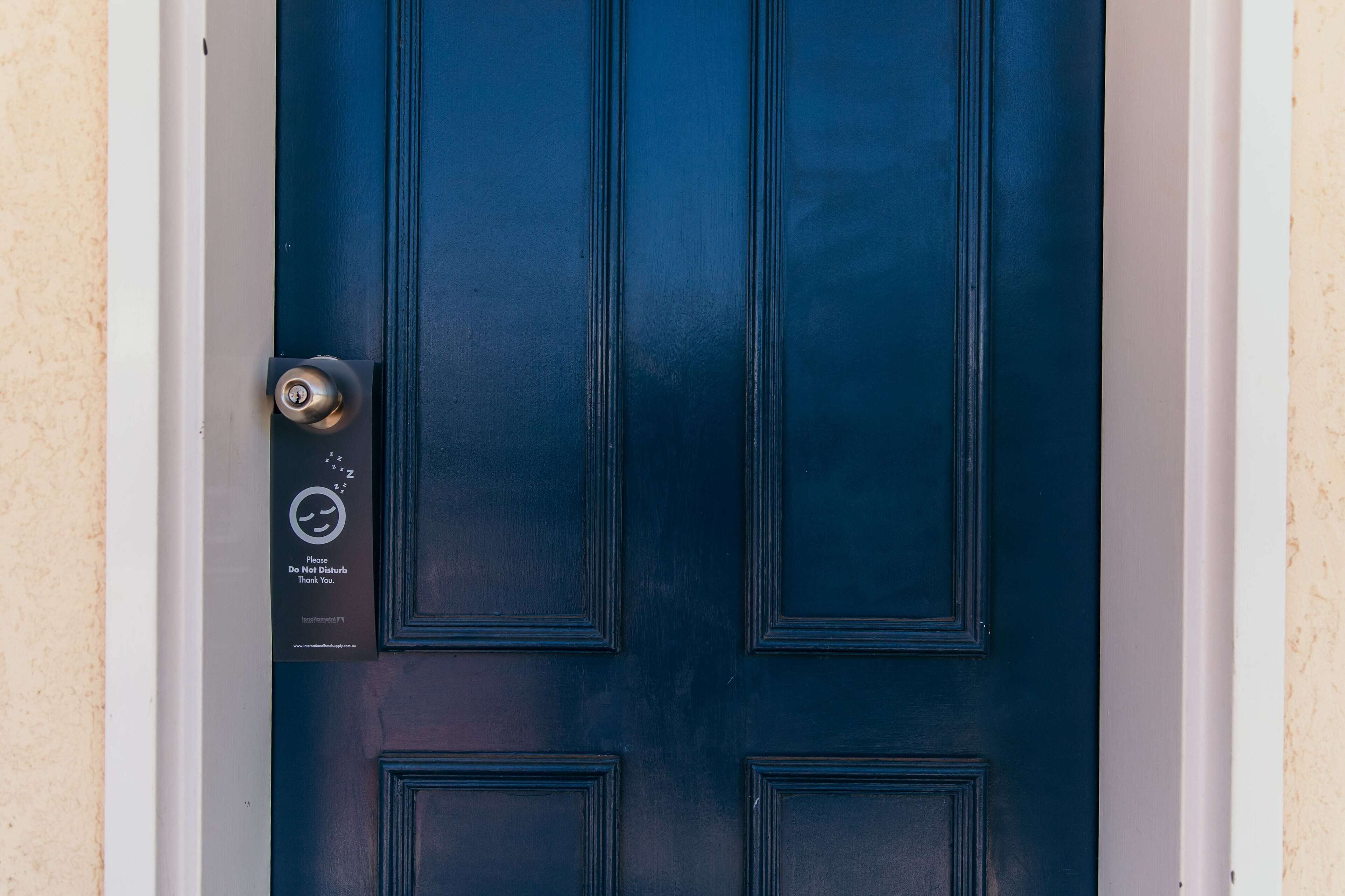 Una puerta azul oscuro con una cerradura y un cartel que dice 'No molestar, gracias'.