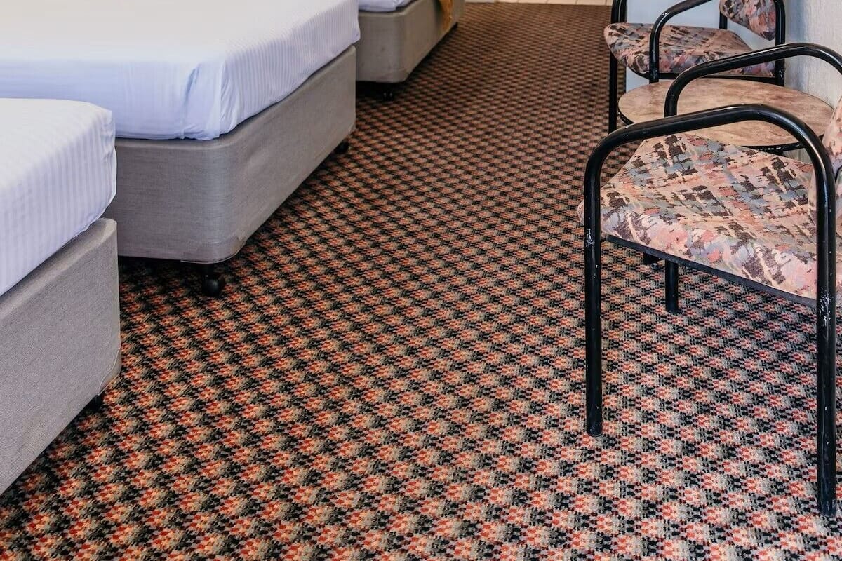 A hotel room with two beds, a desk, and a chair.