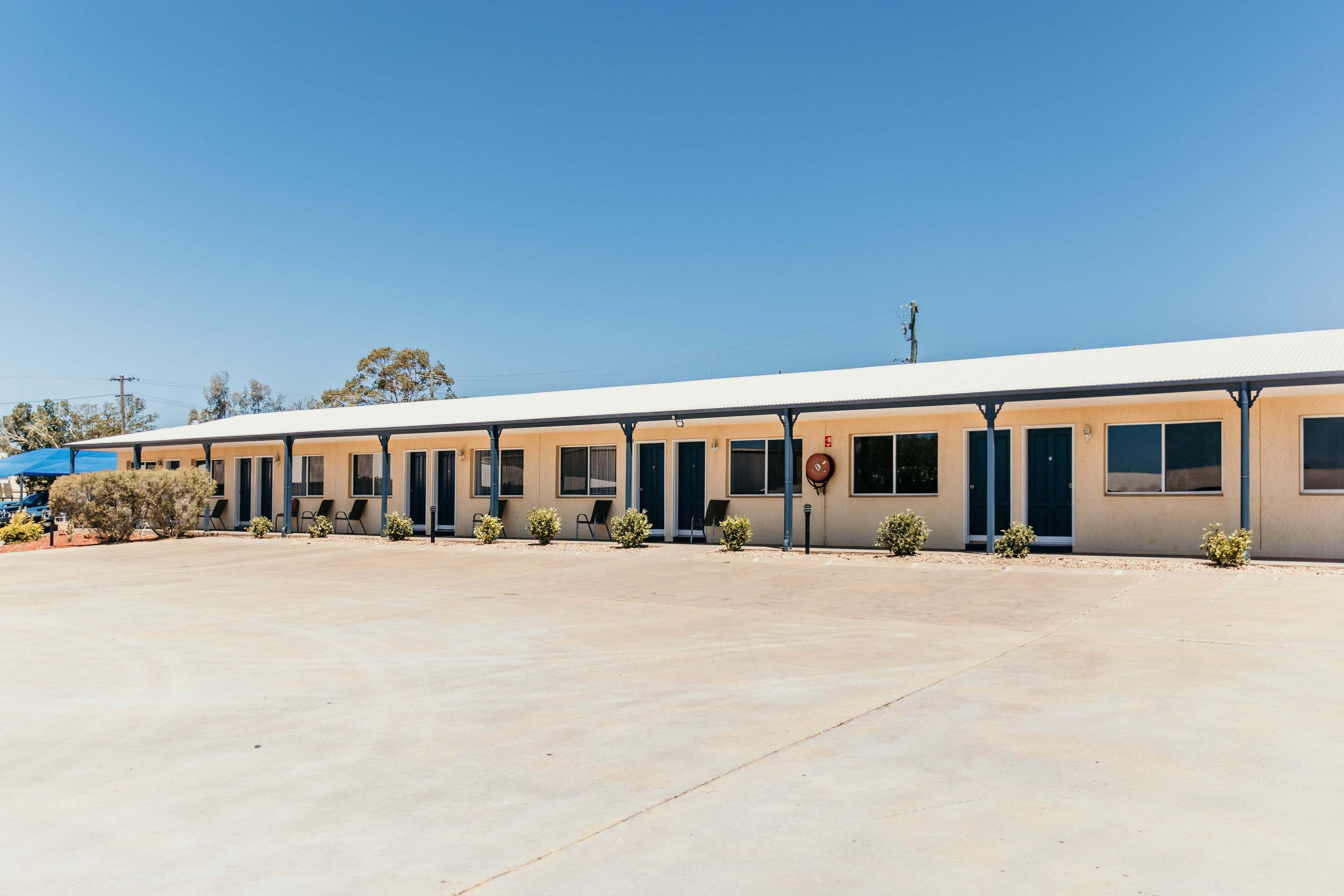 A motel with a row of rooms, each with a door and windows.