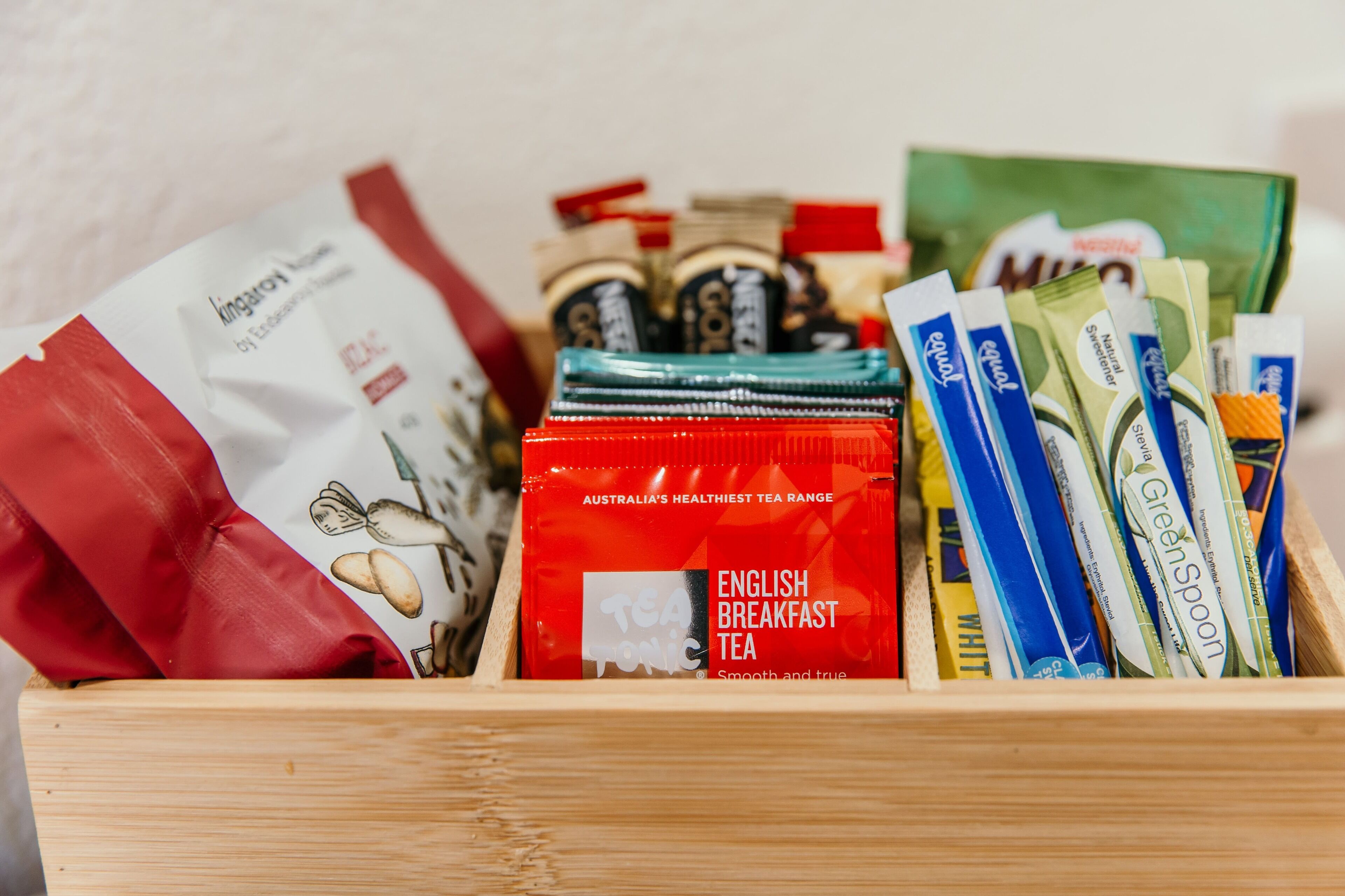 A wooden box containing various tea packets and a red bag labeled "English Breakfast Tea."