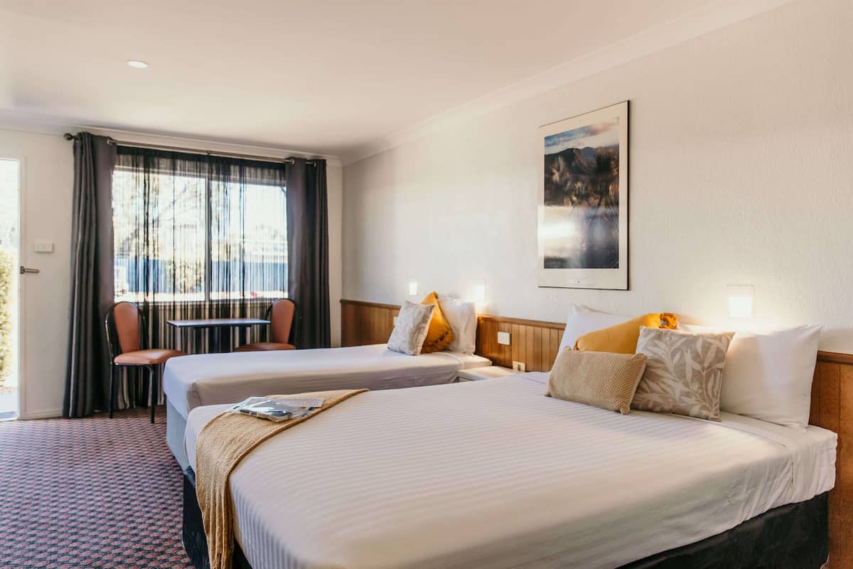 A hotel room with two beds, a dining table, and a chair.
