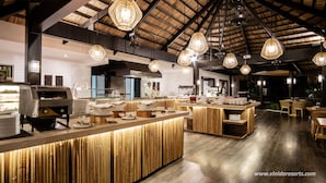 A modern restaurant with a central counter, hanging lights, and a wooden ceiling. - Miniloc Island Resort (El Nido)