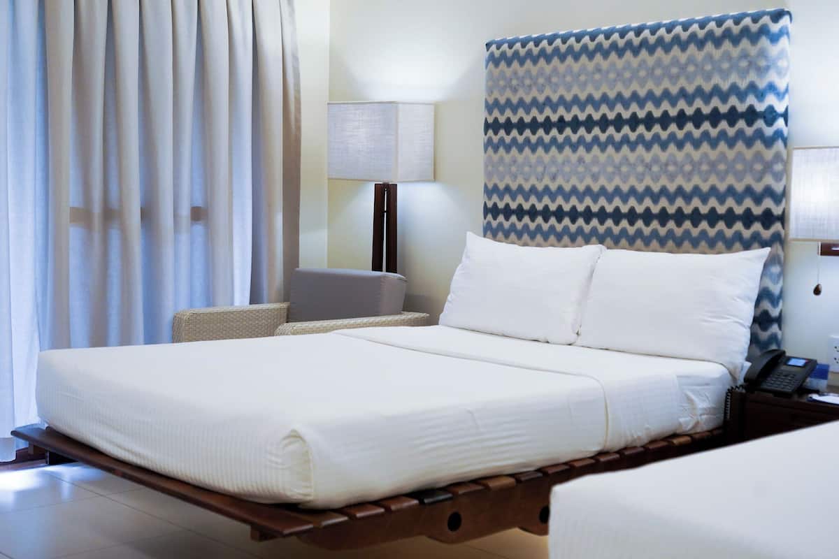 Ein Hotelzimmer mit einem Bett, einem Nachttisch, einer Lampe und einem gemusterten Kopfteil.