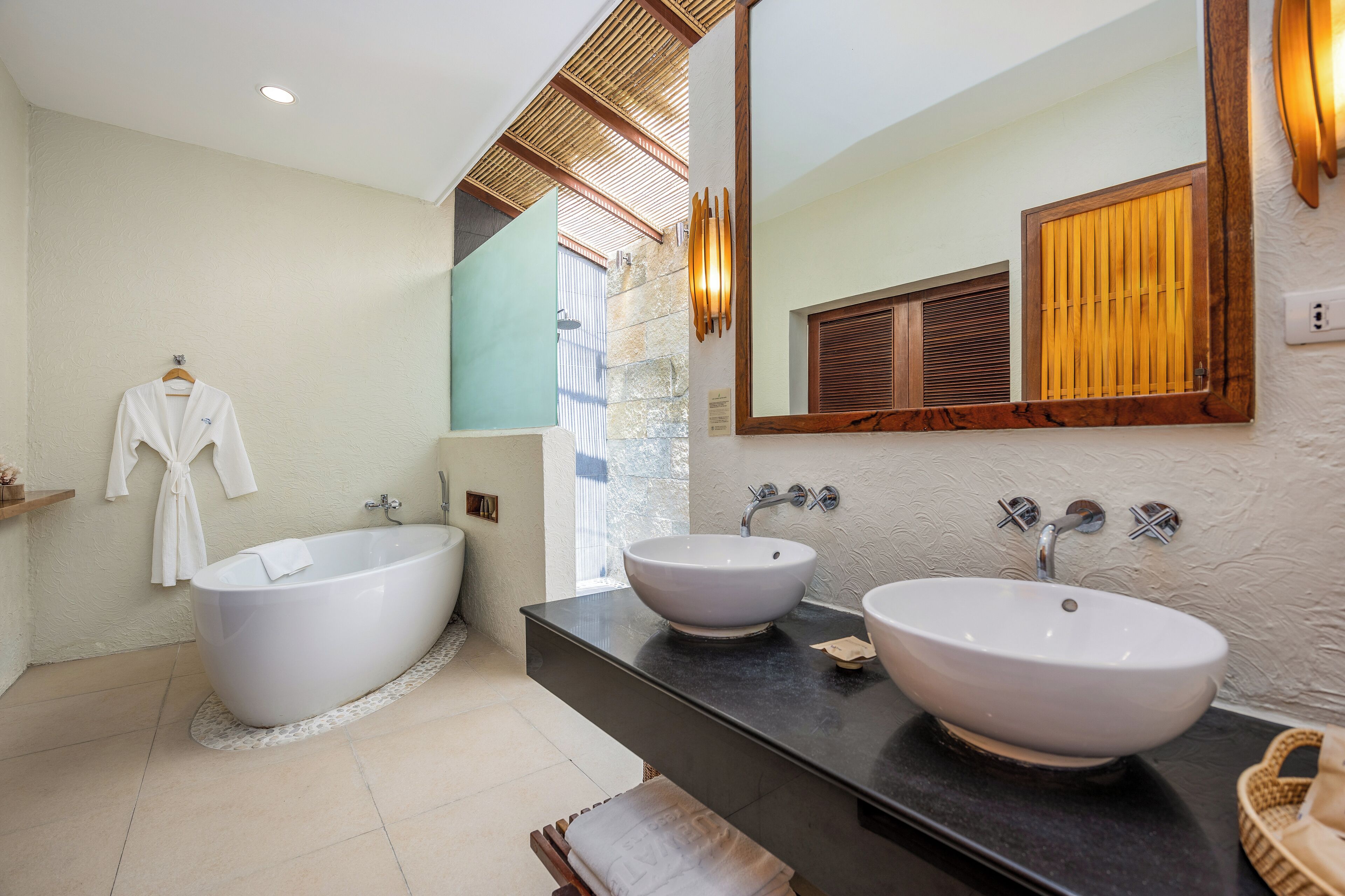 Un baño moderno con una bañera independiente, dos lavamanos, un espejo grande y techo de madera.