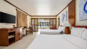 Una habitación de hotel con cama, escritorio, silla, televisor y vista a la piscina.