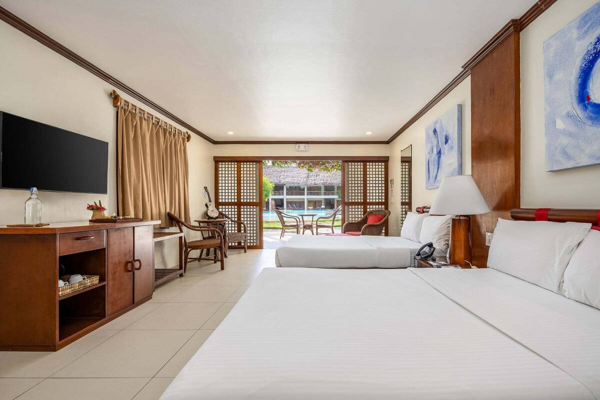 Ein Hotelzimmer mit einem Bett, einem Schreibtisch mit Stuhl, einem Fernseher und Blick auf einen Pool.